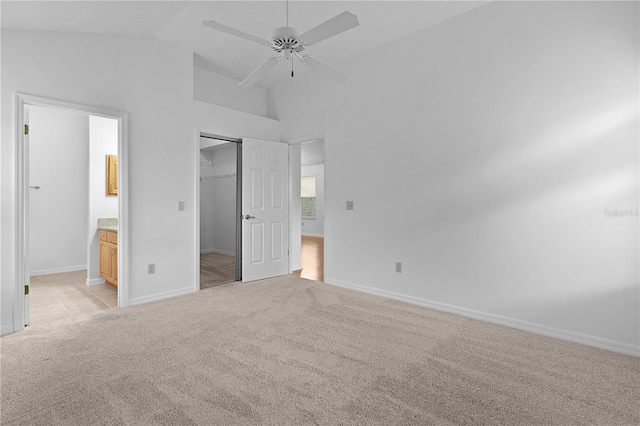 unfurnished bedroom featuring light carpet, baseboards, a ceiling fan, ensuite bathroom, and a closet