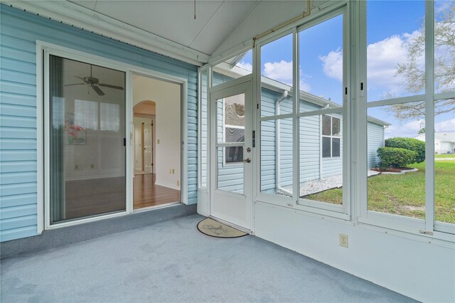 unfurnished sunroom with arched walkways, lofted ceiling, and a ceiling fan