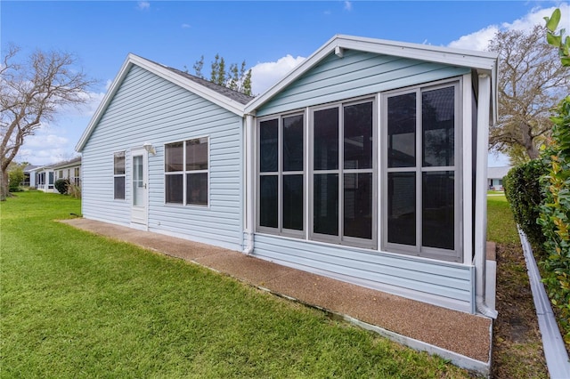 view of property exterior with a lawn and a sunroom