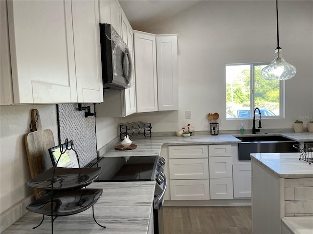 kitchen with stainless steel appliances, hanging light fixtures, a sink, and white cabinets