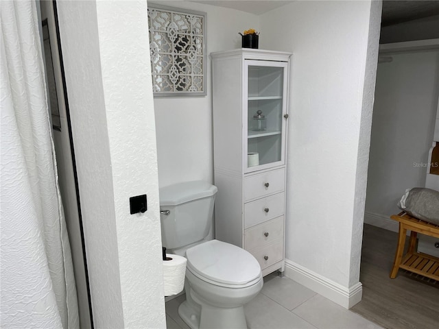 bathroom with toilet, baseboards, and wood finished floors