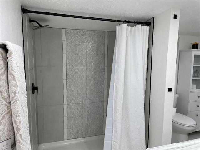 full bath with toilet, a shower stall, and a textured ceiling