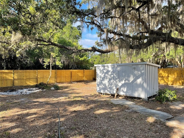 view of yard with a fenced backyard, a storage unit, and an outdoor structure