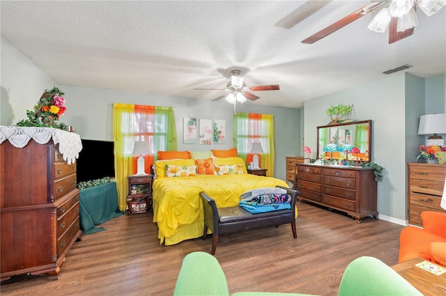 bedroom with a ceiling fan, a textured ceiling, visible vents, and wood finished floors