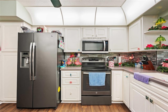 kitchen with white cabinets, decorative backsplash, wood finished floors, stainless steel appliances, and light countertops