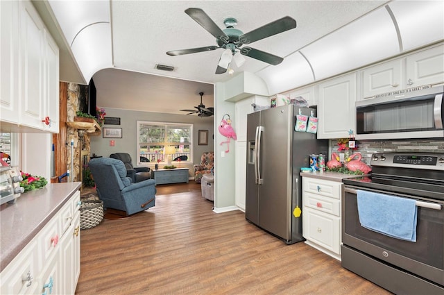 kitchen featuring light wood finished floors, visible vents, open floor plan, stainless steel appliances, and white cabinetry