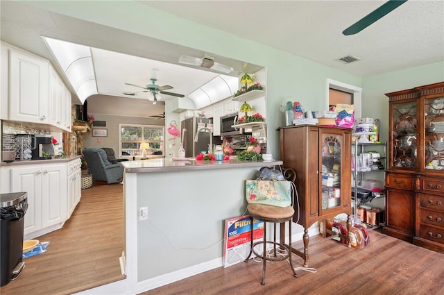 kitchen with ceiling fan, stainless steel appliances, visible vents, white cabinetry, and light wood finished floors