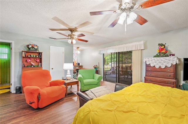 bedroom featuring access to exterior, a ceiling fan, a textured ceiling, and wood finished floors