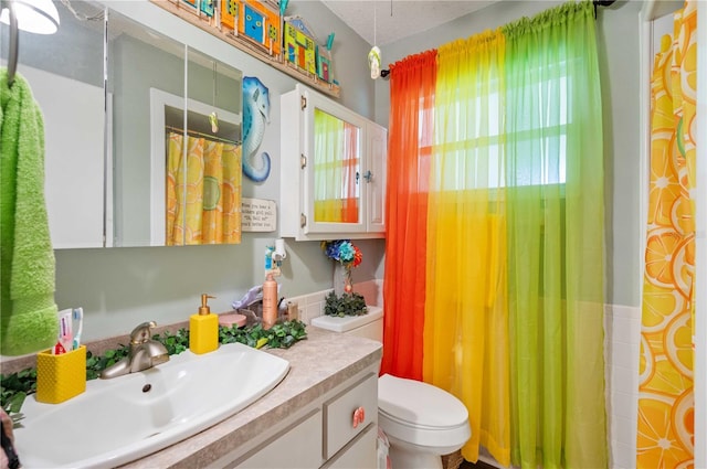 full bath with vanity, toilet, and a textured ceiling