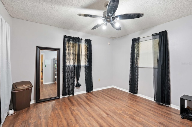 spare room featuring a ceiling fan, a textured ceiling, baseboards, and wood finished floors