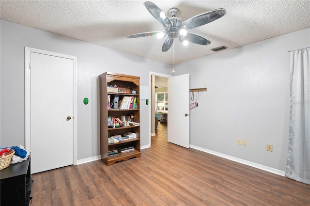 interior space featuring visible vents, a ceiling fan, a textured ceiling, wood finished floors, and baseboards