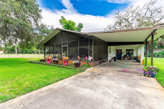 exterior space featuring a sunroom, an attached carport, concrete driveway, and a front yard