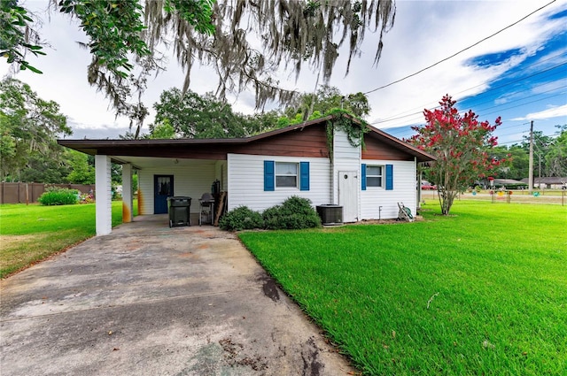 single story home featuring concrete driveway, an attached carport, a front lawn, and fence