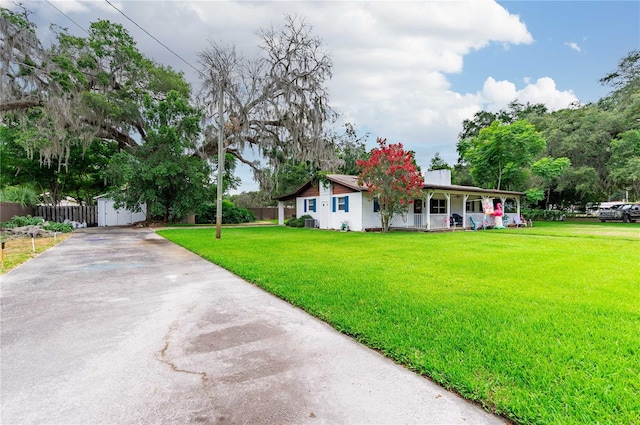 ranch-style house with covered porch, an outdoor structure, fence, a storage unit, and a front yard