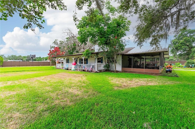 rear view of property featuring a sunroom, fence, metal roof, and a yard