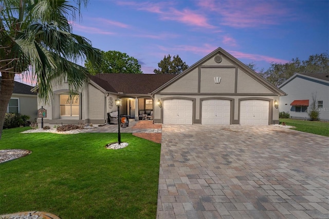 view of front of home featuring a garage, decorative driveway, a front yard, and stucco siding