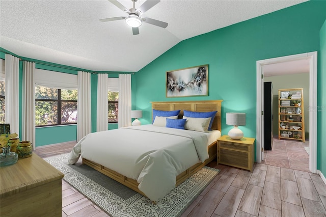 bedroom with ceiling fan, a textured ceiling, vaulted ceiling, and wood finished floors