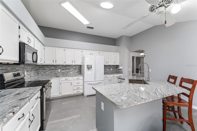 kitchen featuring black microwave, lofted ceiling, white refrigerator with ice dispenser, a sink, and stainless steel electric range oven