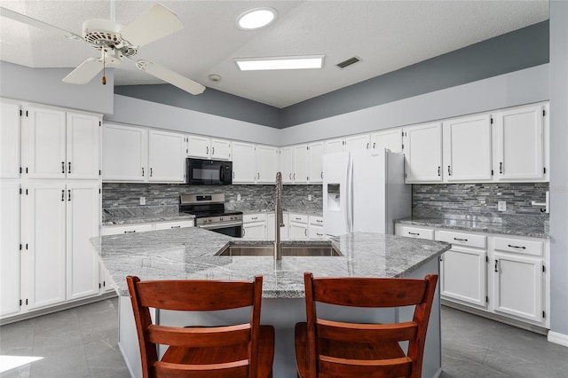 kitchen with black microwave, a sink, visible vents, electric stove, and white fridge with ice dispenser