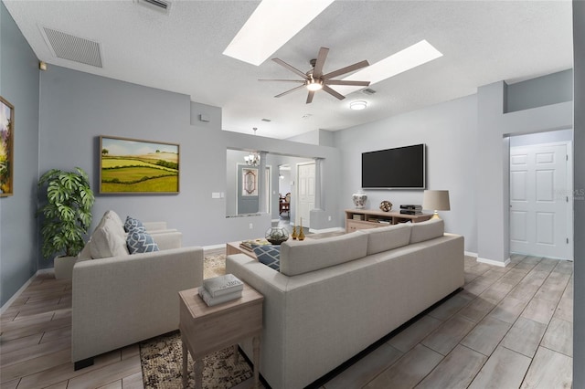 living area with visible vents, baseboards, wood tiled floor, a textured ceiling, and ceiling fan with notable chandelier