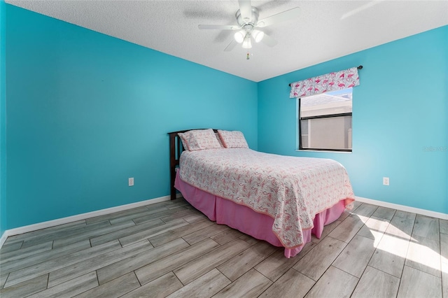 bedroom with ceiling fan, wood finish floors, a textured ceiling, and baseboards