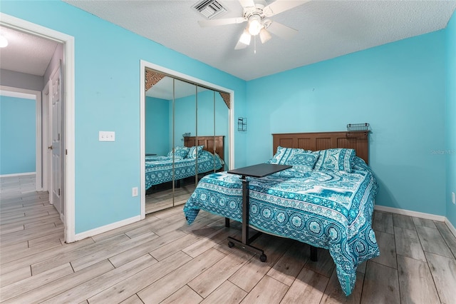 bedroom featuring baseboards, visible vents, wood finished floors, a textured ceiling, and a closet