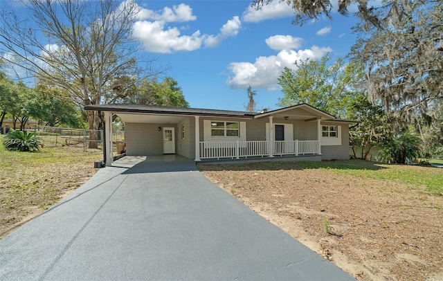 ranch-style home featuring a carport, fence, covered porch, and driveway