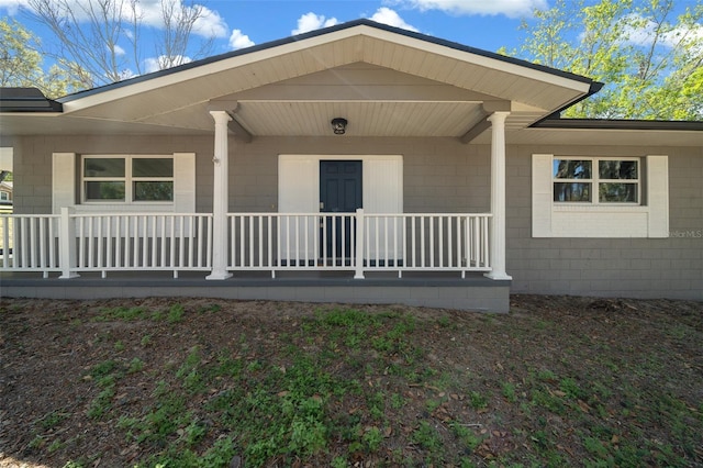 entrance to property with a porch and concrete block siding