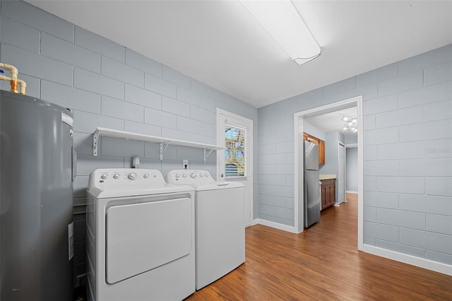 washroom featuring baseboards, washer and clothes dryer, dark wood finished floors, gas water heater, and laundry area