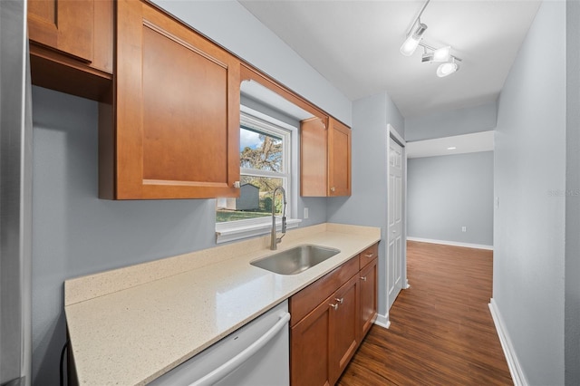 kitchen with baseboards, rail lighting, white dishwasher, dark wood-style floors, and a sink