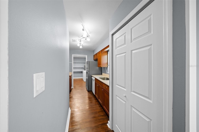 interior space featuring visible vents, dark wood-type flooring, baseboards, rail lighting, and a sink