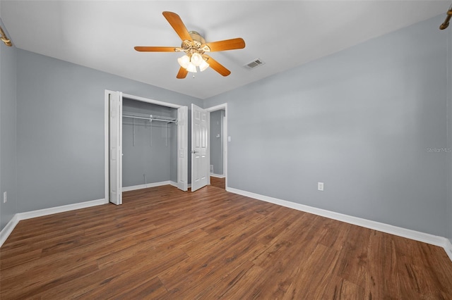 unfurnished bedroom featuring visible vents, ceiling fan, baseboards, wood finished floors, and a closet