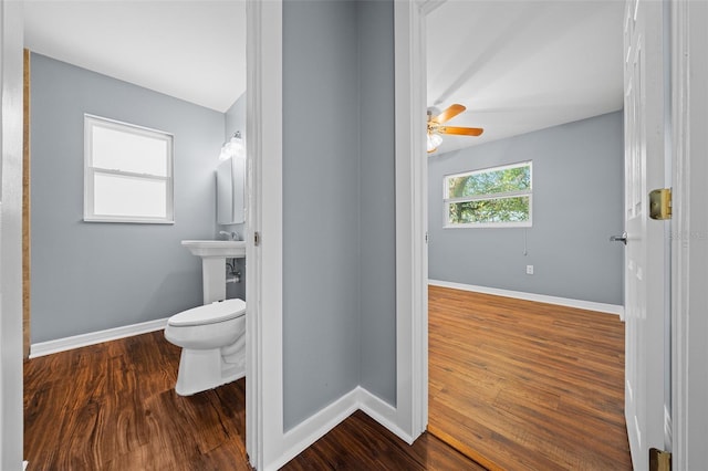 half bath featuring baseboards, toilet, and wood finished floors