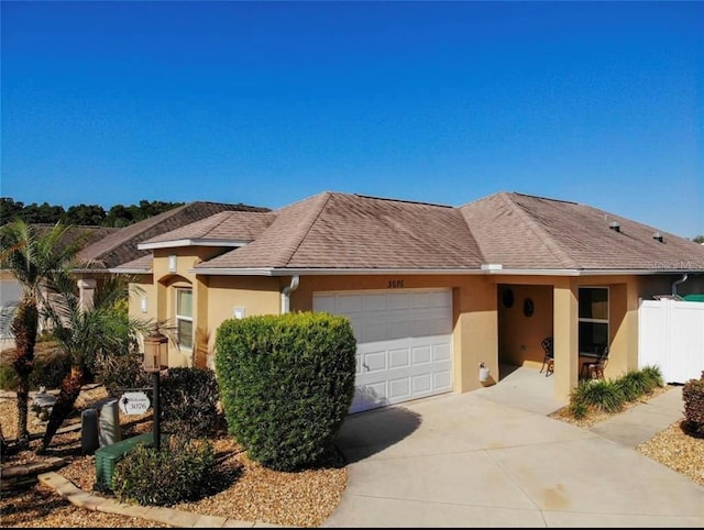 view of front of home featuring an attached garage, fence, concrete driveway, roof with shingles, and stucco siding