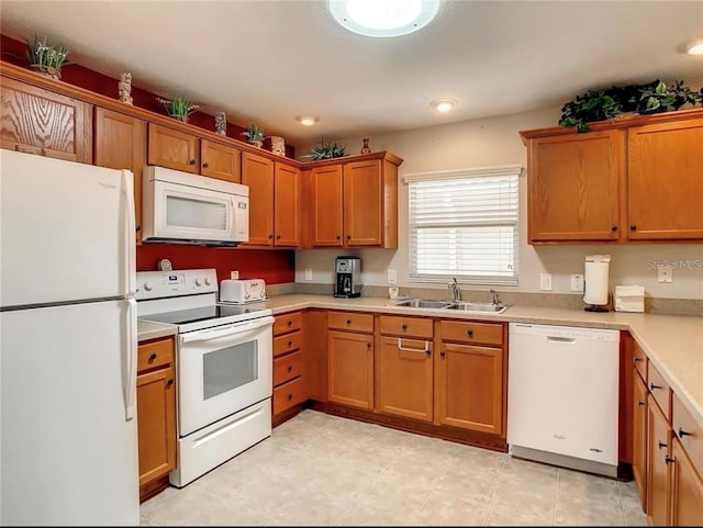 kitchen featuring brown cabinets, white appliances, light countertops, and a sink