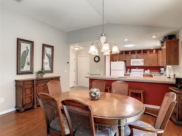 dining room with vaulted ceiling, a chandelier, wood finished floors, and baseboards