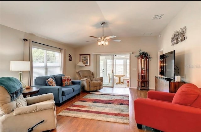 living room featuring a ceiling fan, visible vents, vaulted ceiling, and wood finished floors