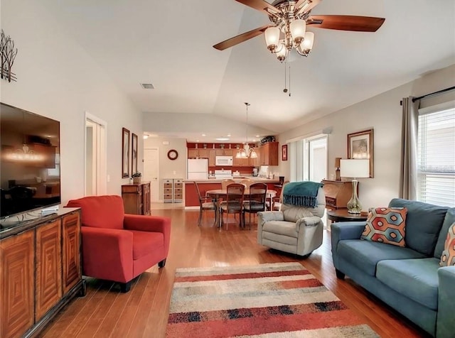 living area with vaulted ceiling, ceiling fan, wood finished floors, and visible vents