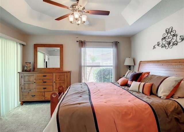 bedroom with carpet, a raised ceiling, and a ceiling fan