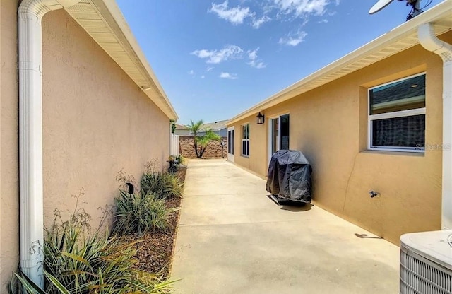 view of side of home featuring a patio area, fence, and stucco siding