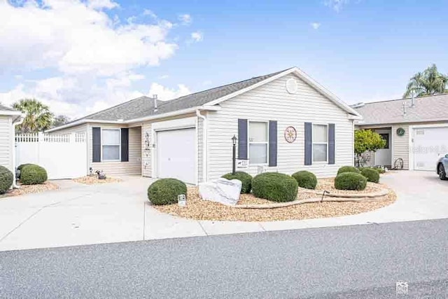 ranch-style home featuring driveway, an attached garage, and fence