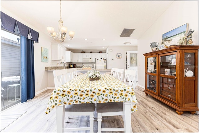 dining area featuring light wood finished floors, visible vents, and baseboards