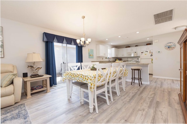 dining space with light wood finished floors, baseboards, visible vents, and a notable chandelier