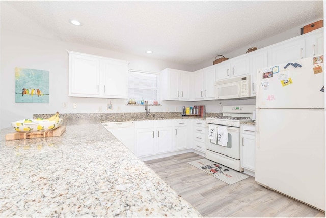 kitchen featuring white appliances, white cabinets, light wood-style floors, a sink, and recessed lighting