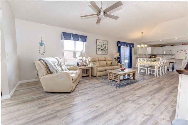 living room featuring light wood-style floors, vaulted ceiling, a textured ceiling, and ceiling fan with notable chandelier