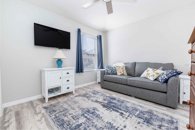 living room with light wood-style floors, ceiling fan, and baseboards