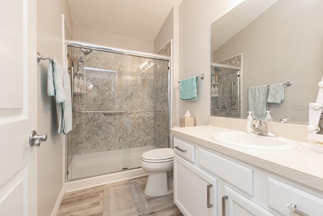 bathroom with a textured ceiling, a stall shower, vanity, and toilet