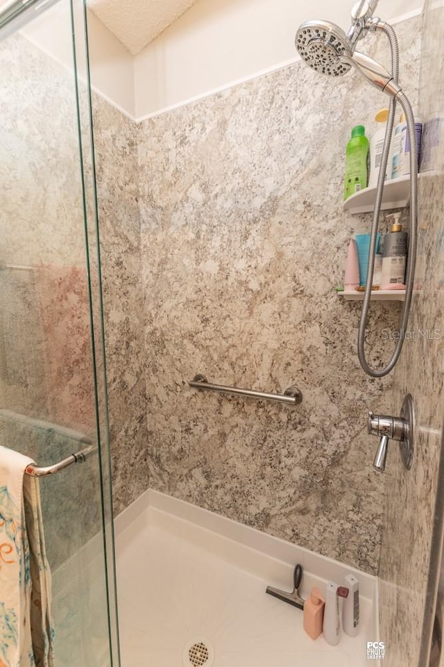 bathroom with a textured ceiling and a shower stall