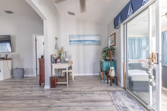 interior space with baseboards, visible vents, arched walkways, wood finished floors, and vaulted ceiling