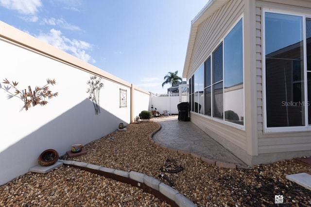 view of side of home featuring a fenced backyard and a patio